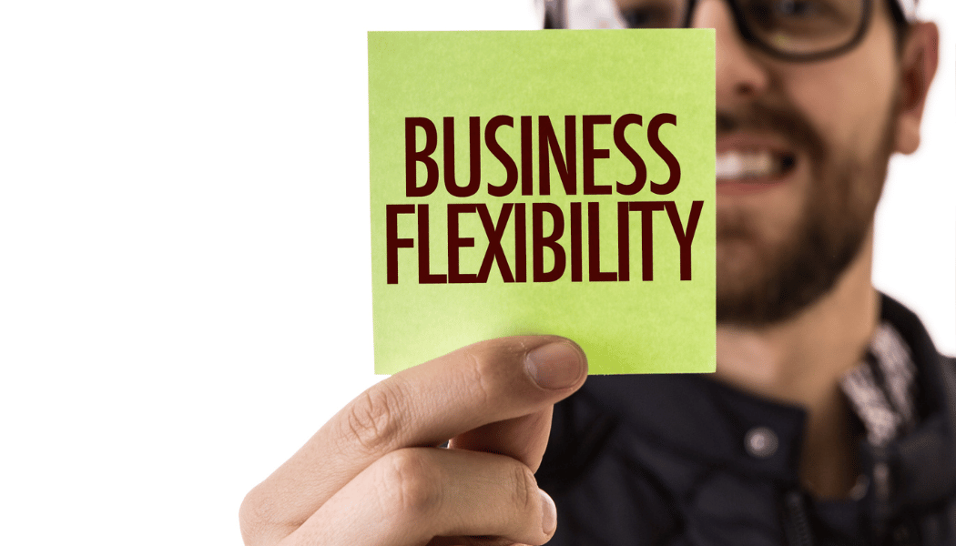 a man holding up a stick note with "Business Flexibility" written over it