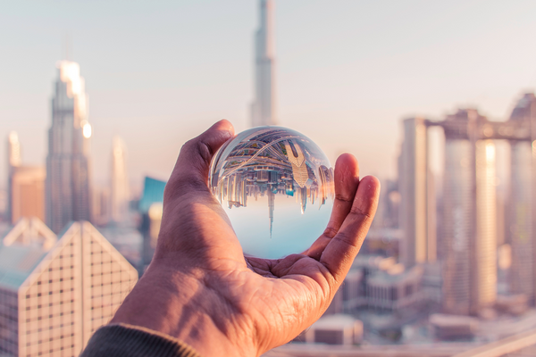 A hand holding a crystal ball that has a reflection of the surroundings